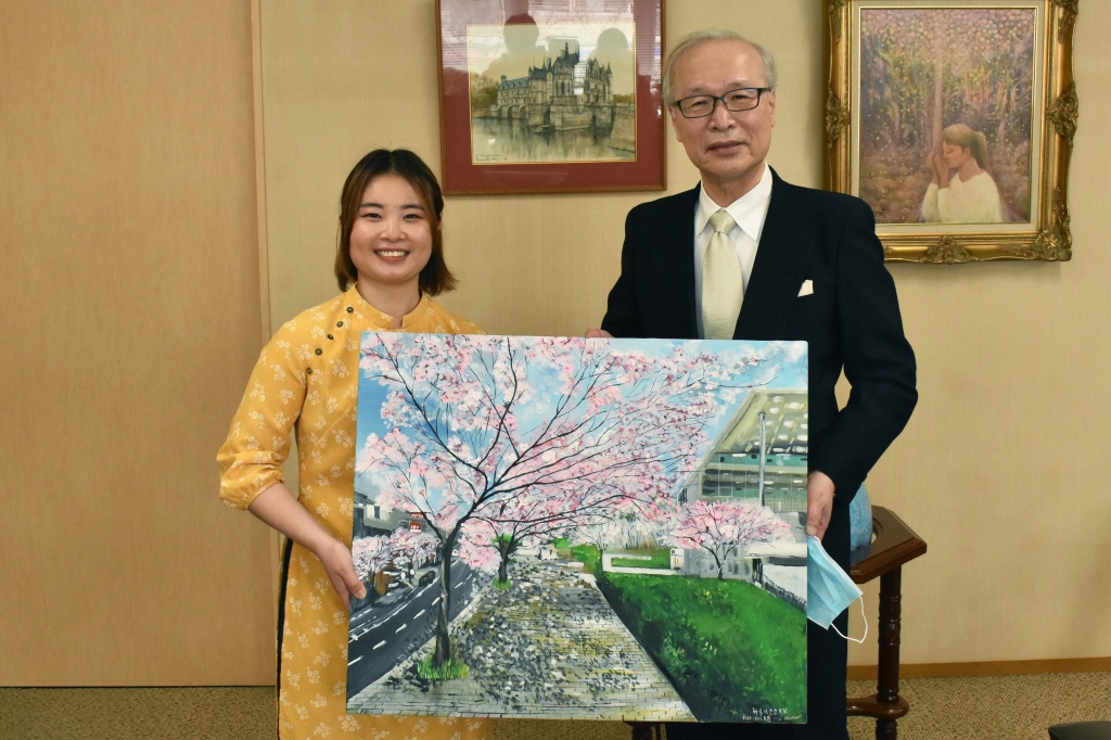 中村学長に横須賀キャンパスの風景画を贈呈するHangさん